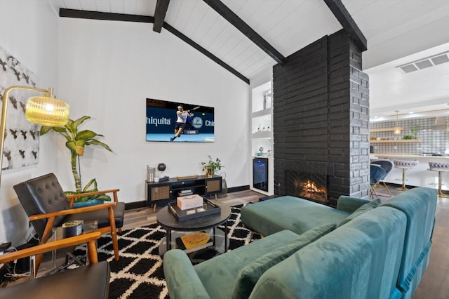 living room featuring hardwood / wood-style flooring, beamed ceiling, high vaulted ceiling, and a brick fireplace