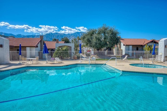 view of swimming pool featuring a mountain view, a patio, and a hot tub