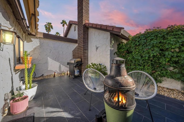 patio terrace at dusk featuring area for grilling