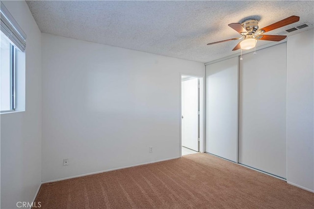 carpeted spare room with ceiling fan and a textured ceiling