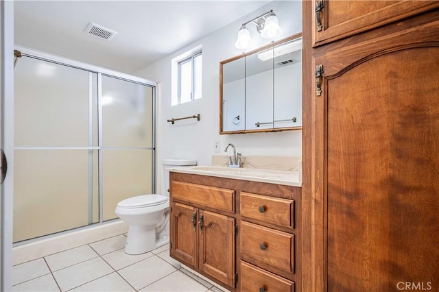 bathroom featuring toilet, vanity, a shower with door, and tile patterned flooring