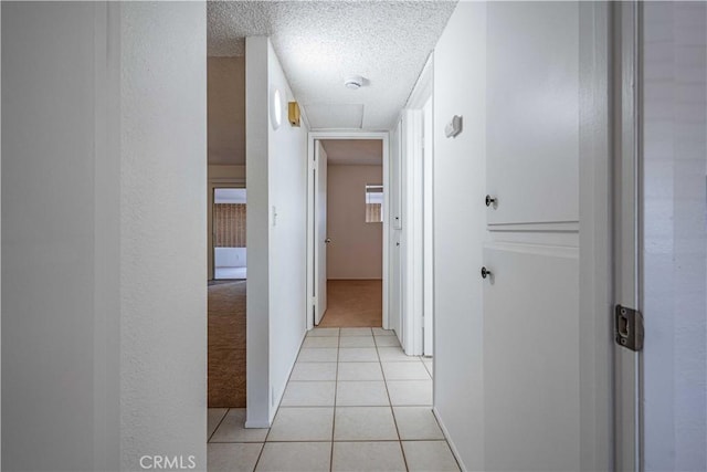 hallway with light tile patterned floors and a textured ceiling