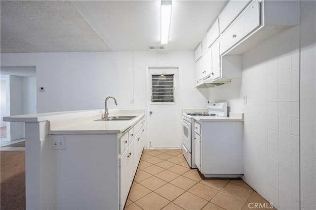 kitchen featuring sink, kitchen peninsula, white gas range oven, and white cabinets