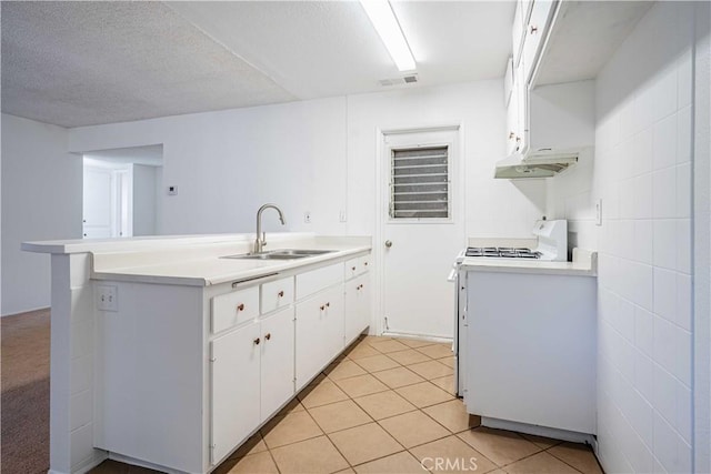 kitchen featuring light tile patterned flooring, sink, white cabinets, white range with gas cooktop, and kitchen peninsula