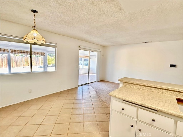 interior space with hanging light fixtures, light tile patterned floors, white cabinets, and a textured ceiling