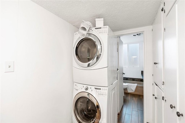 laundry area with a textured ceiling, hardwood / wood-style flooring, and stacked washer and clothes dryer