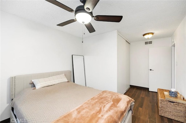 bedroom with a textured ceiling, dark hardwood / wood-style flooring, a closet, and ceiling fan