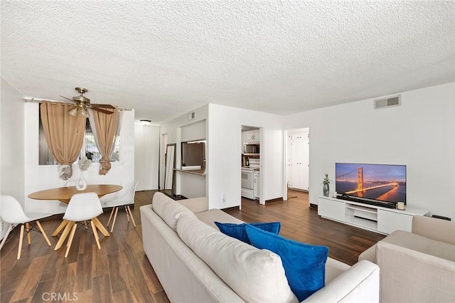 living room with a textured ceiling, ceiling fan, and dark hardwood / wood-style floors