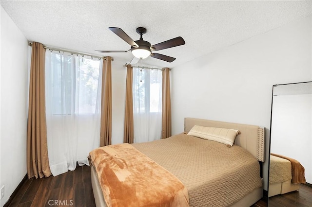 bedroom with a textured ceiling, dark hardwood / wood-style floors, and ceiling fan