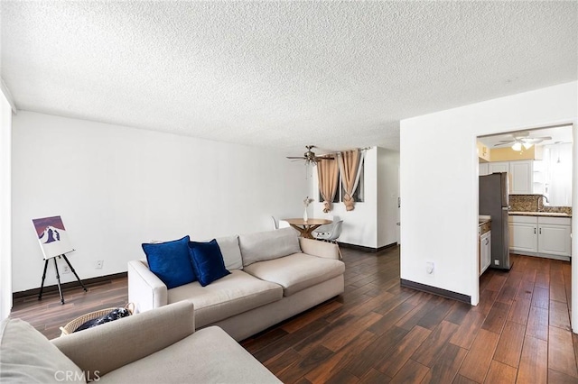 living room with a textured ceiling, dark hardwood / wood-style flooring, ceiling fan, and sink