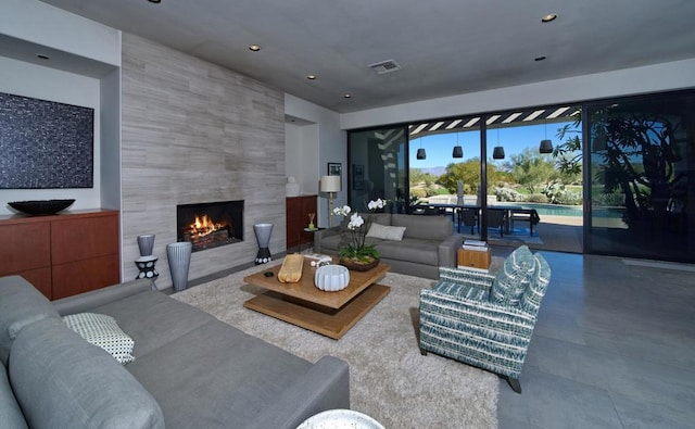 living room featuring a tile fireplace and concrete flooring