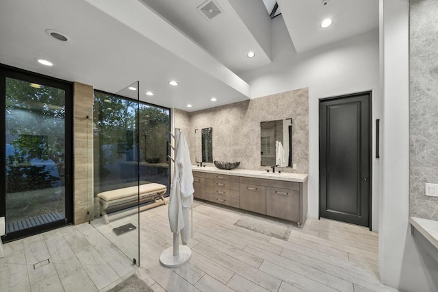 bathroom featuring hardwood / wood-style floors, vanity, expansive windows, and tile walls