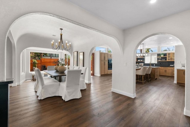 dining space with dark hardwood / wood-style flooring, sink, and a notable chandelier