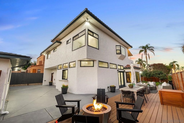 back house at dusk featuring an outdoor living space with a fire pit and a wooden deck