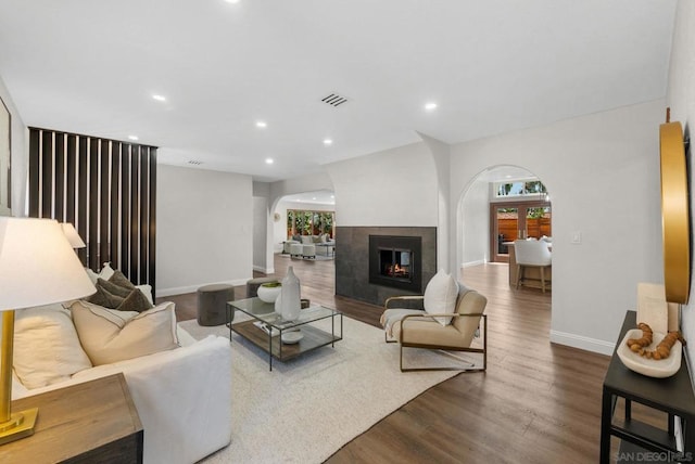 living room featuring a multi sided fireplace and dark hardwood / wood-style floors