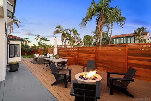 deck at dusk with an outdoor living space with a fire pit