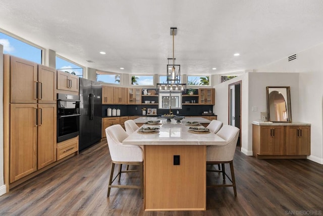 kitchen with a large island, high end refrigerator, decorative light fixtures, dark hardwood / wood-style flooring, and a breakfast bar