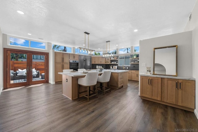 kitchen featuring a breakfast bar area, stainless steel appliances, dark wood-type flooring, pendant lighting, and a center island