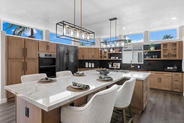 kitchen with dark wood-type flooring, appliances with stainless steel finishes, a kitchen breakfast bar, and a large island