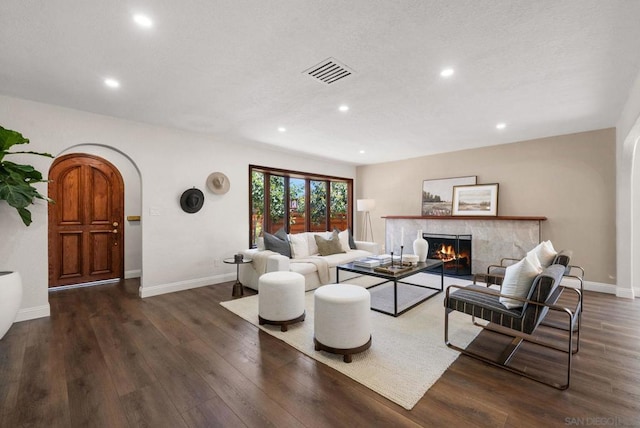 living room with dark wood-type flooring and a tile fireplace