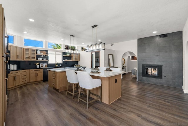 kitchen with a kitchen island, black dishwasher, hanging light fixtures, and a kitchen bar