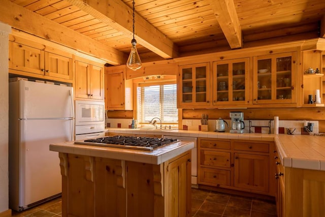 kitchen featuring tile counters, a center island, white appliances, and hanging light fixtures