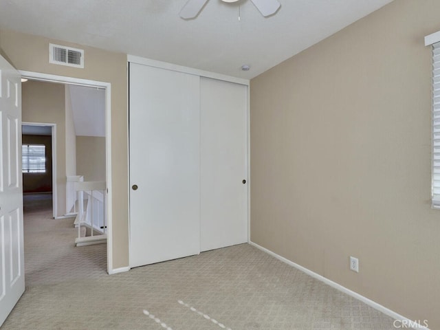 unfurnished bedroom with ceiling fan, a closet, and light carpet