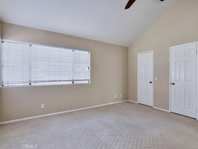 spare room with ceiling fan, light carpet, and vaulted ceiling