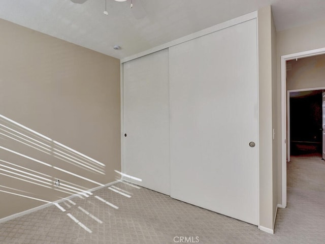 interior space with ceiling fan, a closet, and light carpet