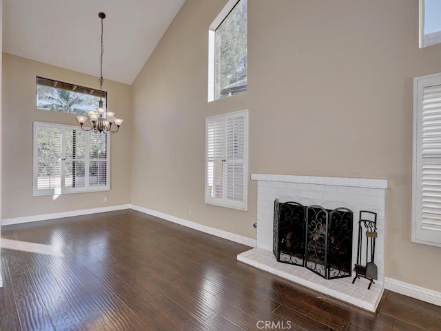 unfurnished living room featuring high vaulted ceiling, dark wood-type flooring, a notable chandelier, and a fireplace