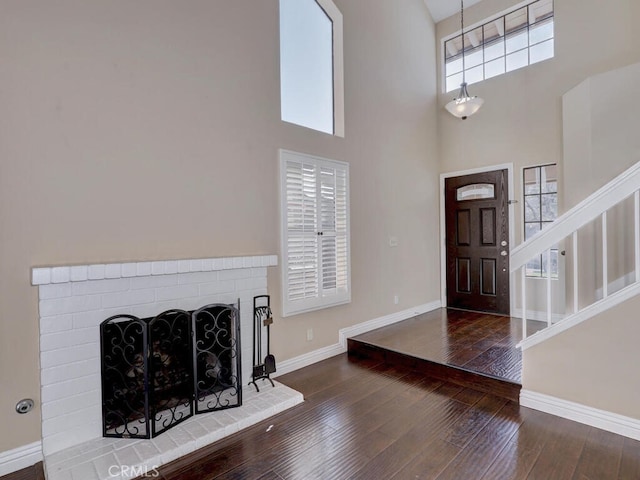 foyer entrance with a brick fireplace, dark hardwood / wood-style flooring, and a high ceiling