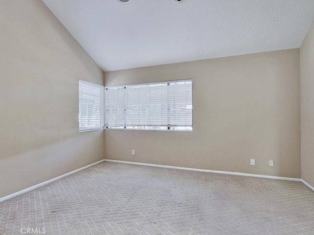 carpeted empty room featuring vaulted ceiling