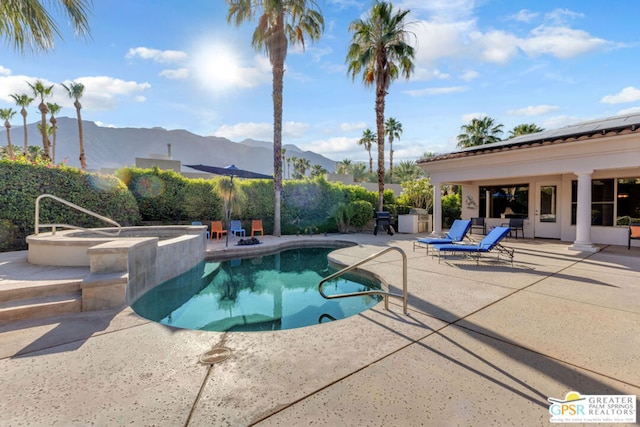 view of pool featuring a mountain view, an in ground hot tub, and a patio