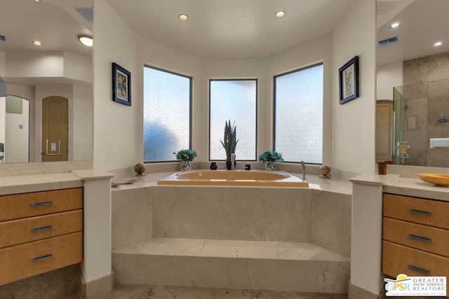 bathroom featuring vanity, a healthy amount of sunlight, and plus walk in shower