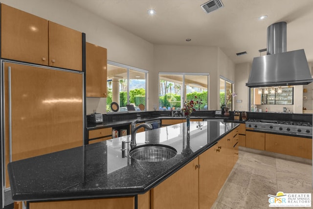 kitchen featuring sink, island exhaust hood, dark stone countertops, a center island with sink, and appliances with stainless steel finishes