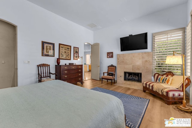 bedroom featuring hardwood / wood-style flooring and a tiled fireplace