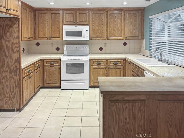 kitchen with light tile patterned floors, backsplash, sink, and white appliances