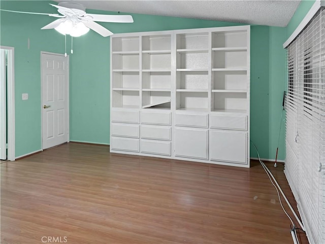 unfurnished bedroom featuring ceiling fan, light wood-type flooring, a textured ceiling, and lofted ceiling