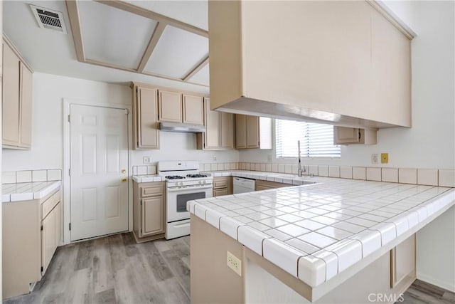 kitchen featuring tile countertops, sink, white appliances, kitchen peninsula, and light wood-type flooring