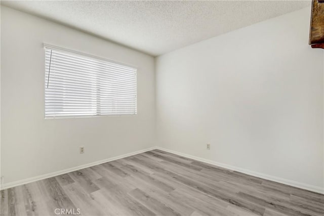 unfurnished room featuring light hardwood / wood-style flooring and a textured ceiling