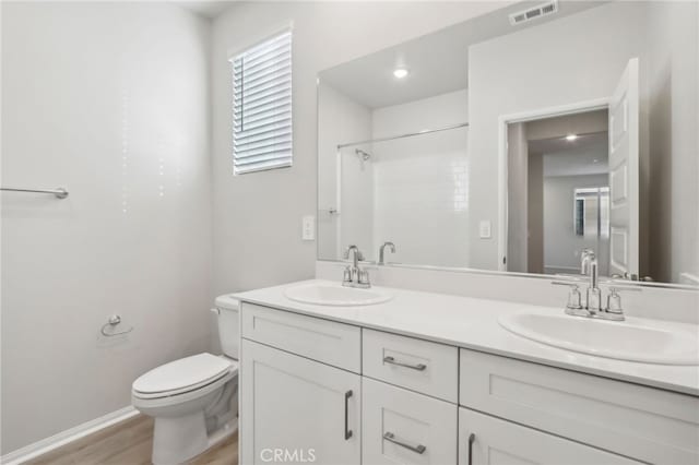 bathroom featuring walk in shower, vanity, toilet, and hardwood / wood-style floors