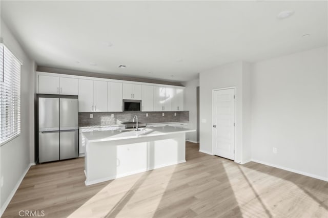 kitchen featuring sink, appliances with stainless steel finishes, white cabinetry, an island with sink, and decorative backsplash