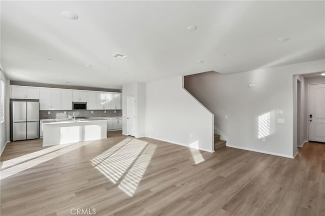 unfurnished living room with sink and light wood-type flooring