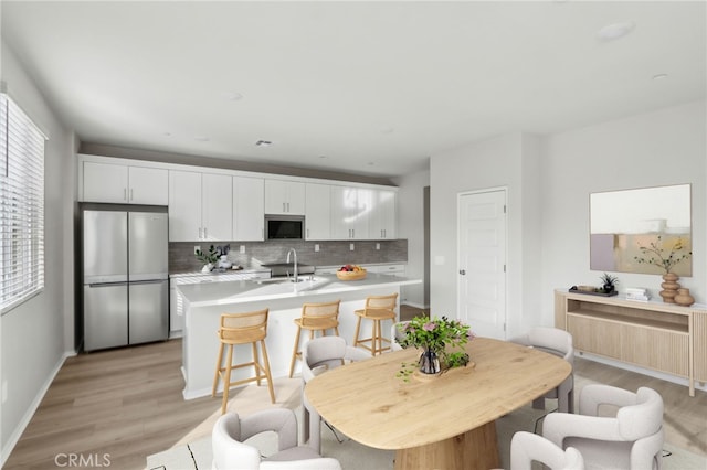 kitchen with sink, white cabinetry, tasteful backsplash, appliances with stainless steel finishes, and light hardwood / wood-style floors