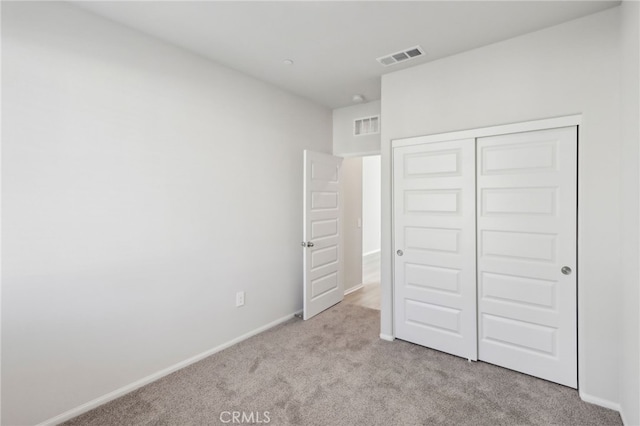 unfurnished bedroom with light carpet and a closet