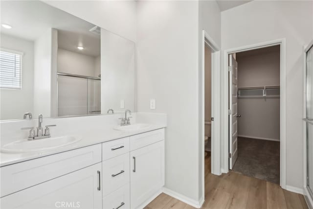 bathroom with vanity, toilet, hardwood / wood-style floors, and a shower with shower door