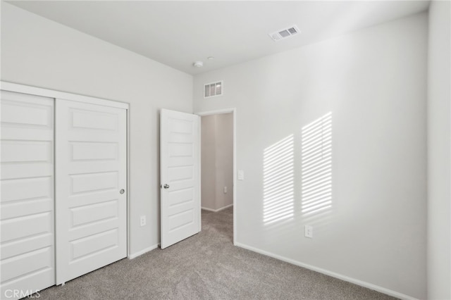 unfurnished bedroom with light carpet and a closet