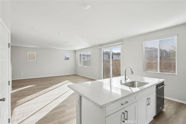 kitchen featuring sink, light hardwood / wood-style floors, white cabinets, and a center island with sink