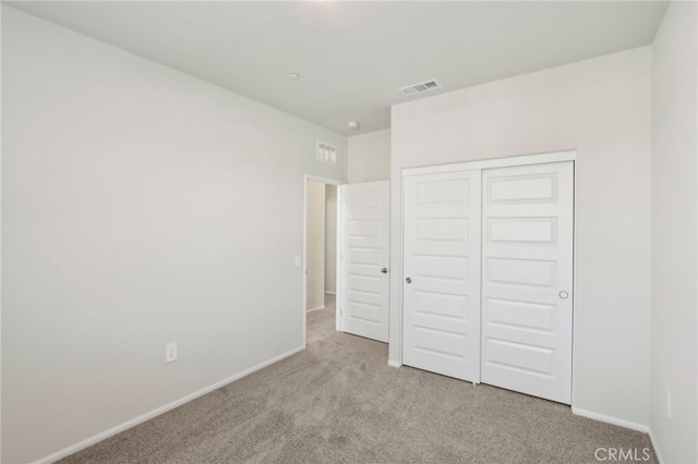 unfurnished bedroom with light colored carpet and a closet