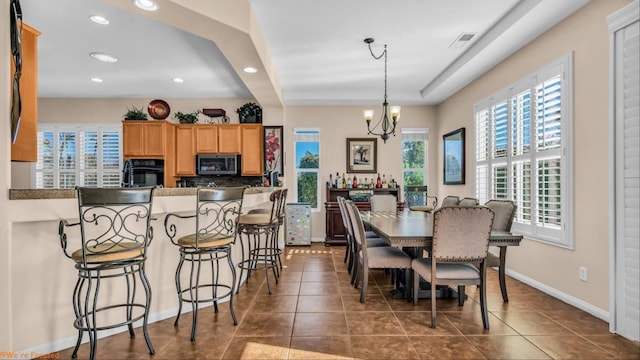 dining room with dark tile patterned flooring and a notable chandelier